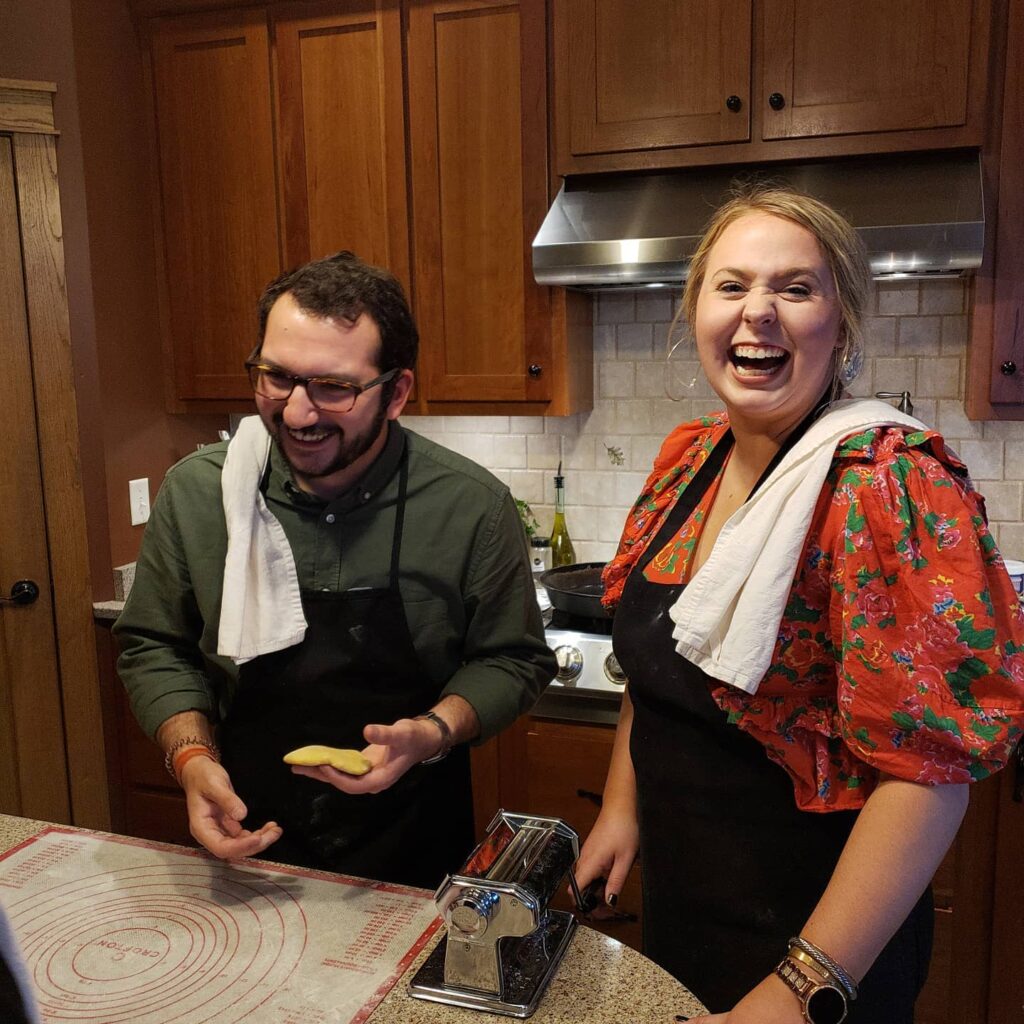 Two students laugh while having fun making pasta