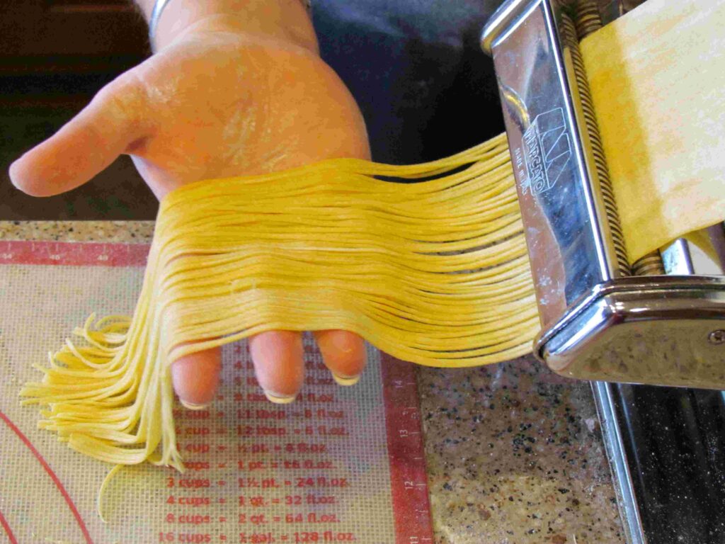 Making pasta using a hand crank pasta machine in PastaNooga's gourmet kitchen